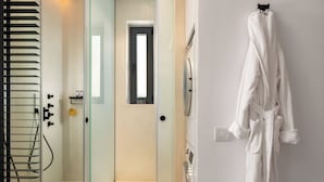 Une salle de bain moderne avec une douche à l’italienne en verre, une baignoire blanche et un peignoir blanc accroché au mur.