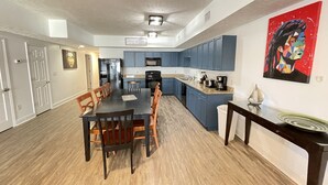 A modern kitchen with blue cabinets, a large island, and a dining area with wooden chairs.
