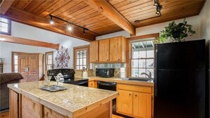 A kitchen with wooden cabinets, granite countertops, a black refrigerator, and a microwave. - Rustic, Private, Cozy Cabin Getaway in Mountains of Big Canoe (Big Canoe)