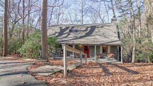 A rustic cabin with a wooden exterior, a red door, and a small porch with a bench. - Rustic, Private, Cozy Cabin Getaway in Mountains of Big Canoe (Big Canoe)