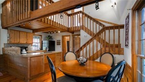 A wooden dining area with a round table and chairs, a kitchen with wooden cabinets, and a staircase with exposed beams. - Rustic, Private, Cozy Cabin Getaway in Mountains of Big Canoe (Big Canoe)