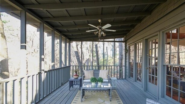 A covered porch with a ceiling fan, a table with chairs, and a view of trees through large windows. - Rustic, Private, Cozy Cabin Getaway in Mountains of Big Canoe (Big Canoe)