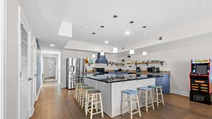 Een moderne keuken met een centraal eiland, barstoelen, hanglampen en een retro speelautomaat.