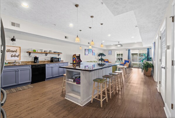 A modern kitchen with a central island, bar stools, and a dining area with a view. - Cloud 9-er (Myrtle Beach)