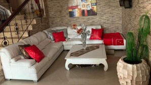 A living room with a white sofa set, a coffee table, a painting on the wall, and a staircase. - Villa 100m from the beach (Mohammedia wilaya de Casablanca)