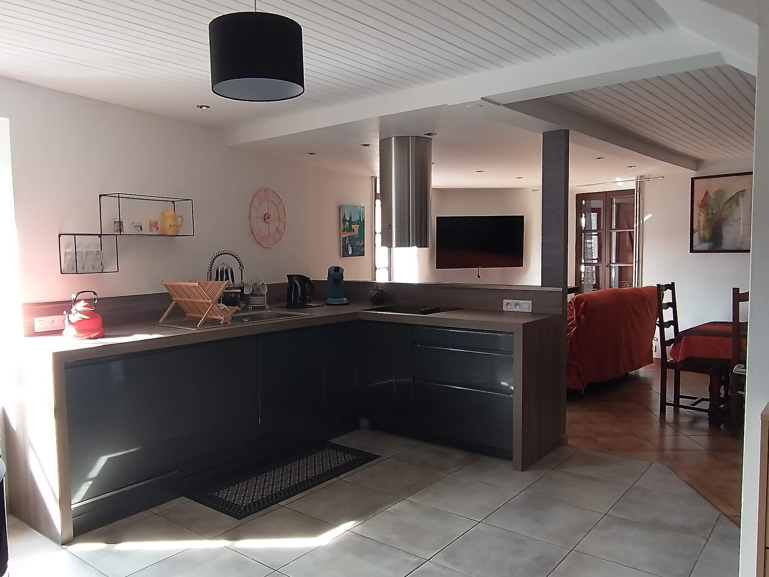 Een moderne keuken met een groot kookeiland, inbouwapparatuur en een eethoek met een rode tafelkleed.