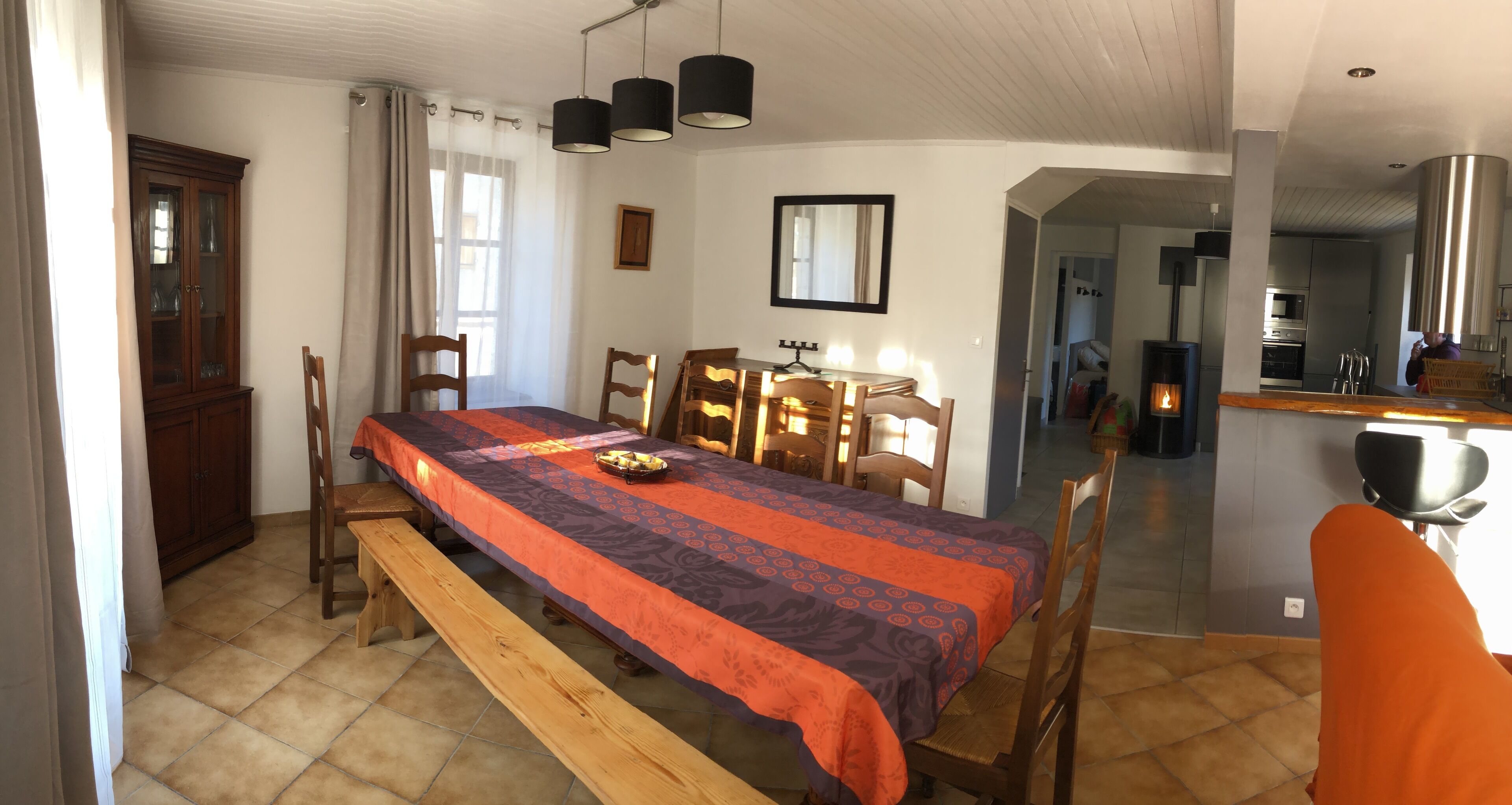 A room with a bed, wooden chairs, a bench, a dining table, and a cabinet.