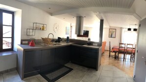 Een moderne keuken met een groot eiland, inbouwapparatuur en een eethoek met een tafel en stoelen.