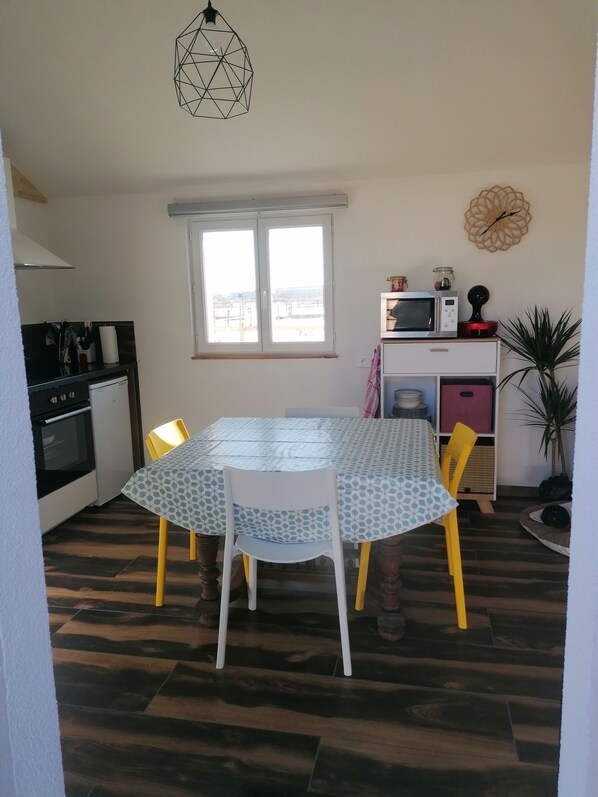 A kitchen with a dining table, chairs, a microwave, and a clock on the wall.