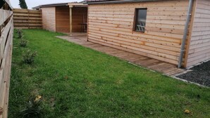 Een houten hut met een klein terras en een raam.