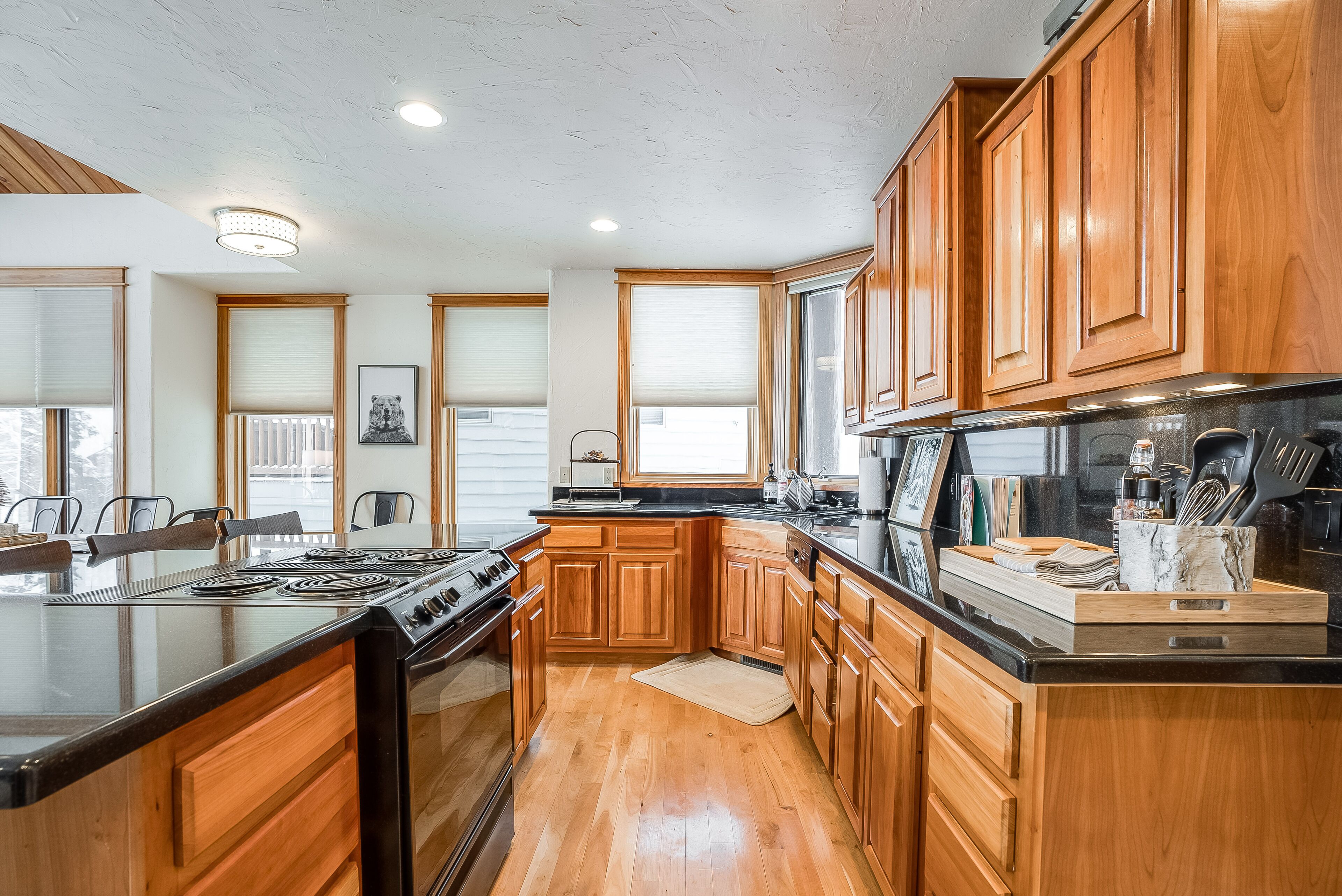 A modern kitchen with wooden cabinets, a large island with a stove, and a black countertop.