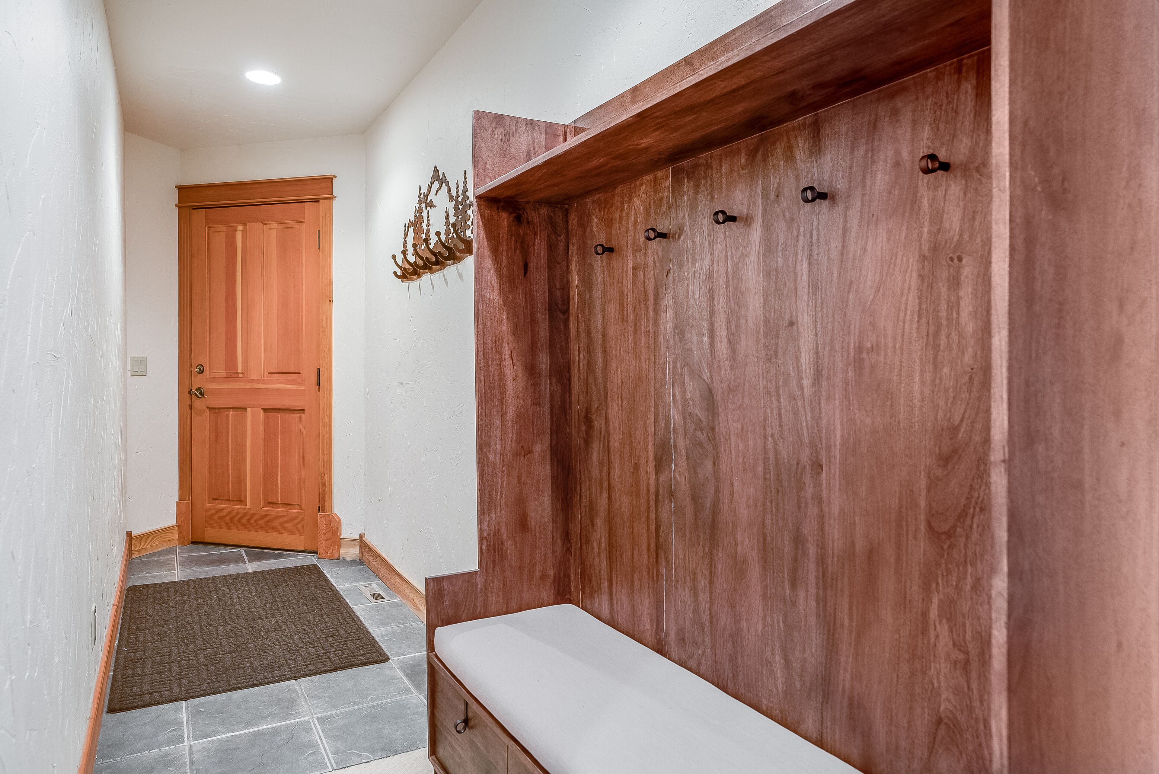 A hallway with a wooden door, a bench, and a coat rack.