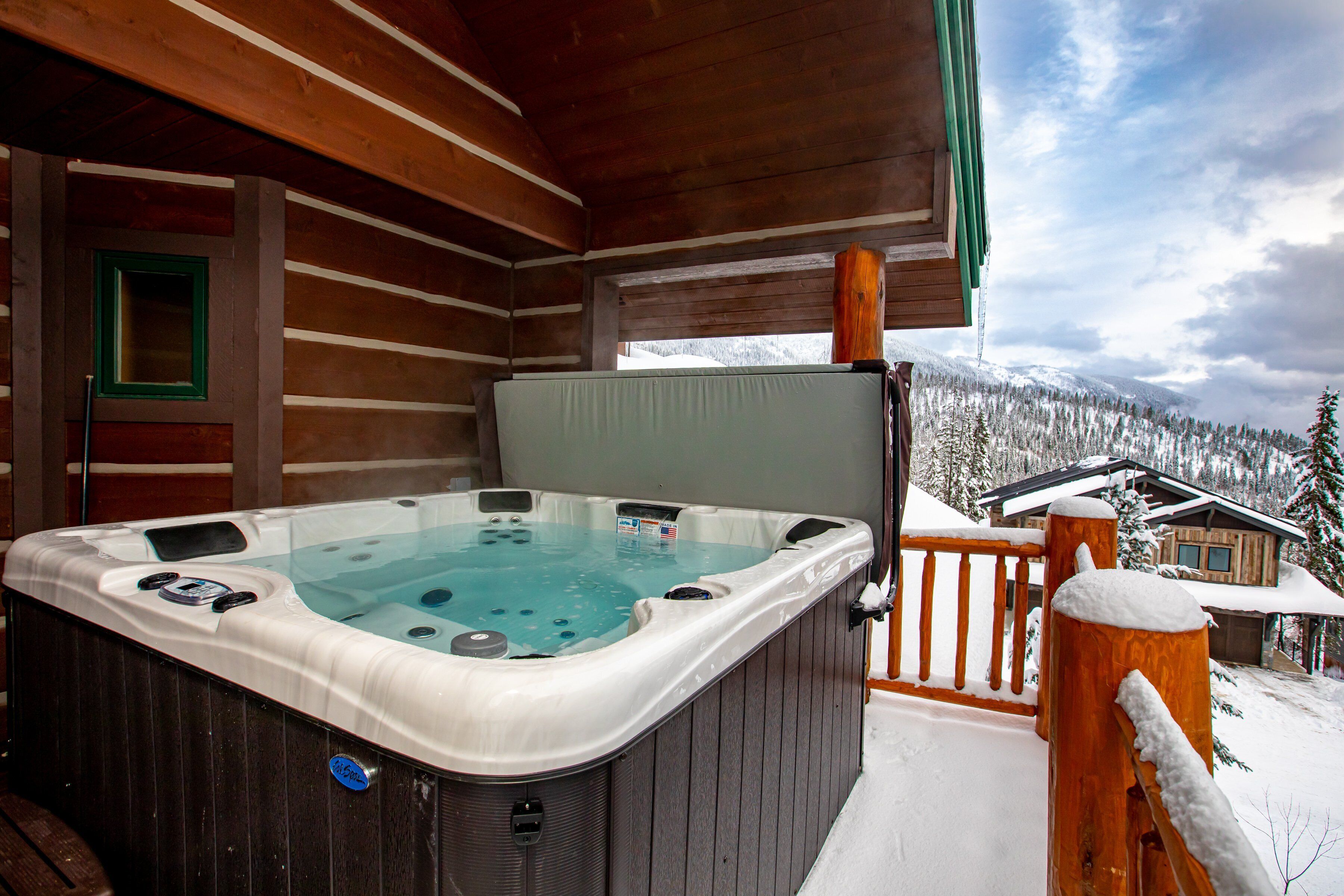 A wooden cabin with a hot tub on a balcony.