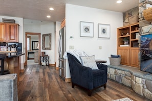 A spacious living area with a dark blue armchair, wooden cabinets, and a stone accent wall.