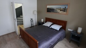 Une chambre à coucher avec un lit en bois, une table de chevet, une lampe et un tableau accroché au mur.