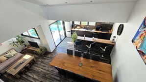 A modern kitchen with a wooden dining table, black bar stools, and a large window overlooking a pool. - La Maline**** Piscine chauffée et salle de jeux (Sainte-Soulle)