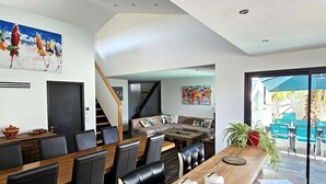 A modern dining area with a wooden table, black chairs, and a view of the outdoors. - La Maline**** Piscine chauffée et salle de jeux (Sainte-Soulle)