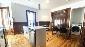 A modern kitchen with wooden flooring, a central island, a built-in dishwasher, and a washing machine.