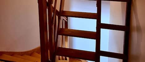 Une échelle en bois dans une pièce dont le sol et le plafond sont en bois, ce dernier étant incliné.