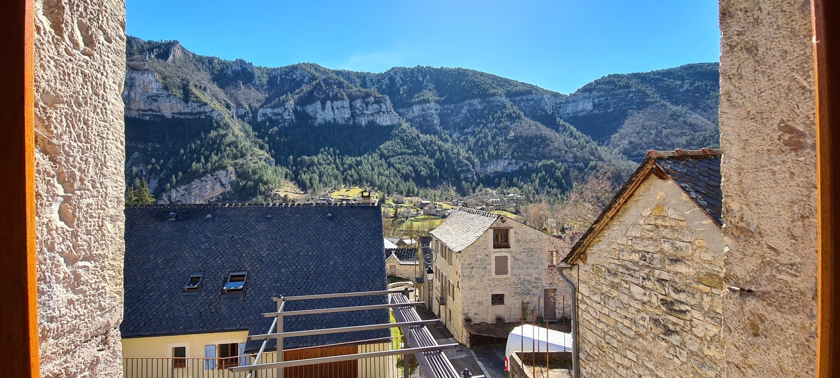 A mountainous landscape with traditional stone buildings, a narrow street, and a clear sky.