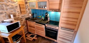 A compact kitchen with wooden cabinets, a microwave, a sink, and a stove.