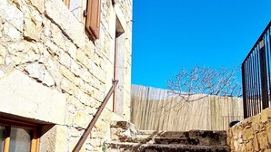 A stone staircase leading up to a building with wooden shutters and a metal railing.