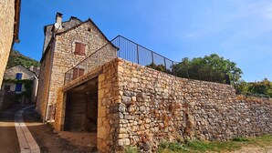 A stone building with a small tower, a metal railing, and a paved path leading to a door.