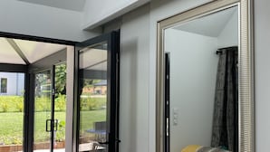 A modern room with a large mirror, sliding glass doors leading to a patio, and a radiator on the wall. - L' Annex ' : charming quiet house with garden close to the beach (Névez)