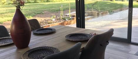 A modern dining area with a wooden table, woven placemats, and dark chairs.