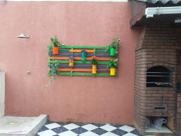 A wall-mounted planter with various plants and a small brick oven. - Penthouse with its own barbecue near Enseada Beach - Guarujá (Guarujá)