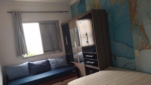 A bedroom with a bed, a sofa bed, a wardrobe, and a window with curtains. - Penthouse with its own barbecue near Enseada Beach - Guarujá (Guarujá)