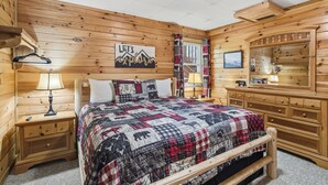 Ein Zimmer einer Holzhütte mit einem Bett, einem Nachttisch, einer Kommode, einem Spiegel und einem Schild mit der Aufschrift 'LET'S EXPLORE'.
