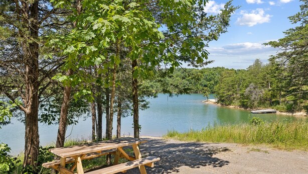 Ein Picknicktisch am See, umgeben von Bäumen.