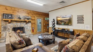 Ein gemütliches Blockhaus-Interieur mit Kamin aus Stein, Holzwänden und einer komfortablen Sitzecke.