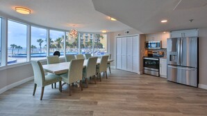 Una cocina amplia con electrodomésticos modernos, ventanas grandes con vistas a la playa y un comedor con mesa y sillas.