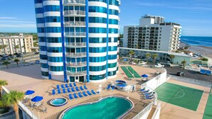 Un hotel con piscina, tumbonas y cancha de tenis.