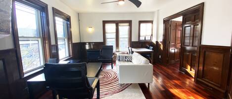 A spacious room with a dining table, chairs, a sofa, and a fireplace.