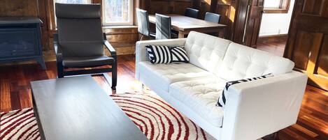 A modern living room with a white sofa, black and white striped pillow, a dark wooden coffee table, and a red and white patterned rug.