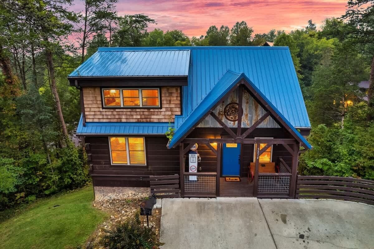 Eine zweistöckige Holzhütte mit blauem Dach, einer Holzterrasse und einem Steinfundament.