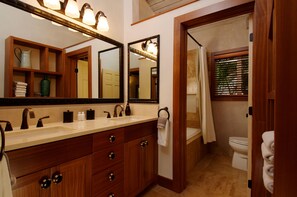 Un bagno con lavabo, specchio e mobile sottolavabo. Si intravede un WC attraverso una porta aperta.