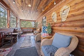 Interno di una baita con pareti in legno, un divano, mobili in vimini e una piccola decorazione con la bandiera americana.