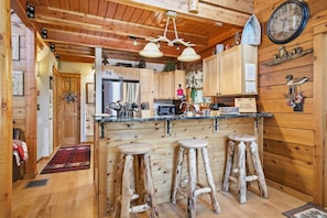 Un interno in legno con cucina, sgabelli da bar, orologio e arredamento rustico.