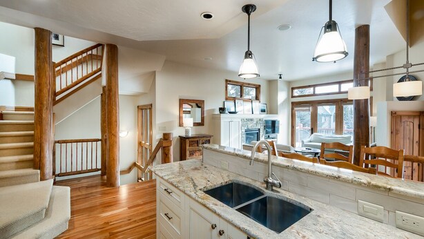 A kitchen with a large island, wooden flooring, and a staircase leading to another level.
