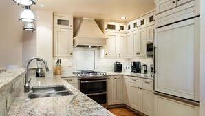 A modern kitchen with white cabinets, a granite countertop, stainless steel appliances, and under-cabinet lighting.