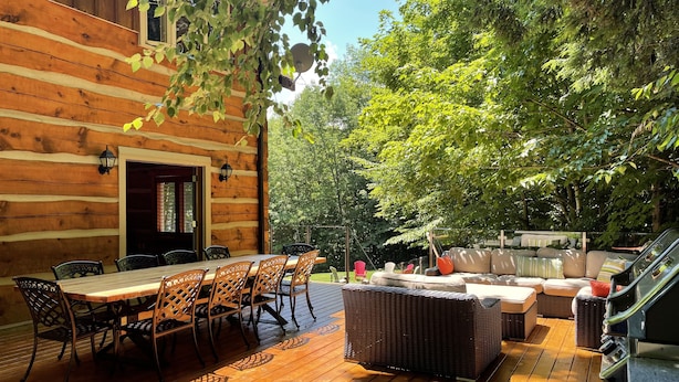 A wooden deck with a dining area, outdoor seating, and a hot tub. - Luxury Log Home, Southern Georgian Bay - Explore Blue Mountain to Tobermory (Annan)