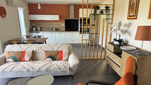 A living room with a sofa, orange chair, and small tables. - Villa Coquelicot - Private swimming pool - Electricity terminal (Moussac)
