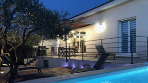 A swimming pool with lounge chairs, a table, and a staircase leading to a covered patio area. - Villa Coquelicot - Private swimming pool - Electricity terminal (Moussac)