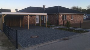 Una casa con entrada cubierta, fachada de ladrillo y un pequeño jardín.