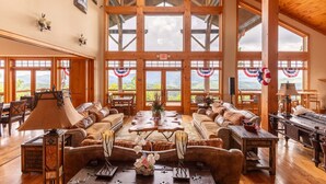 A spacious room with large windows, wooden beams, and a high ceiling.