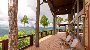 A wooden deck with chairs, a railing, and a view of mountains.